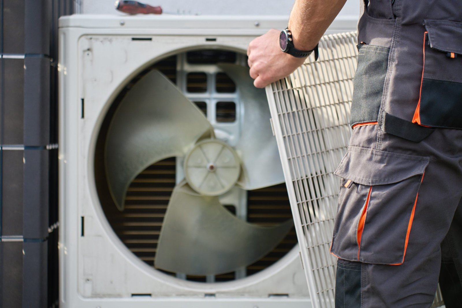 Technicien retirant la grille d'une unité de climatisation extérieure